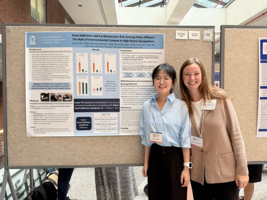 Two women stand smiling in front of a research poster titled Food Addiction and Cardiovascular Risk Among Police Officers at an academic event. The poster displays charts, graphs, and text summarizing their study findings.
