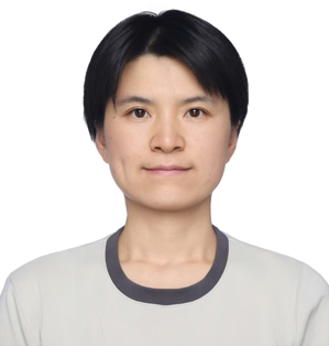 A person with short black hair and a neutral expression, wearing a light-colored shirt with a dark collar, in front of a plain white background.