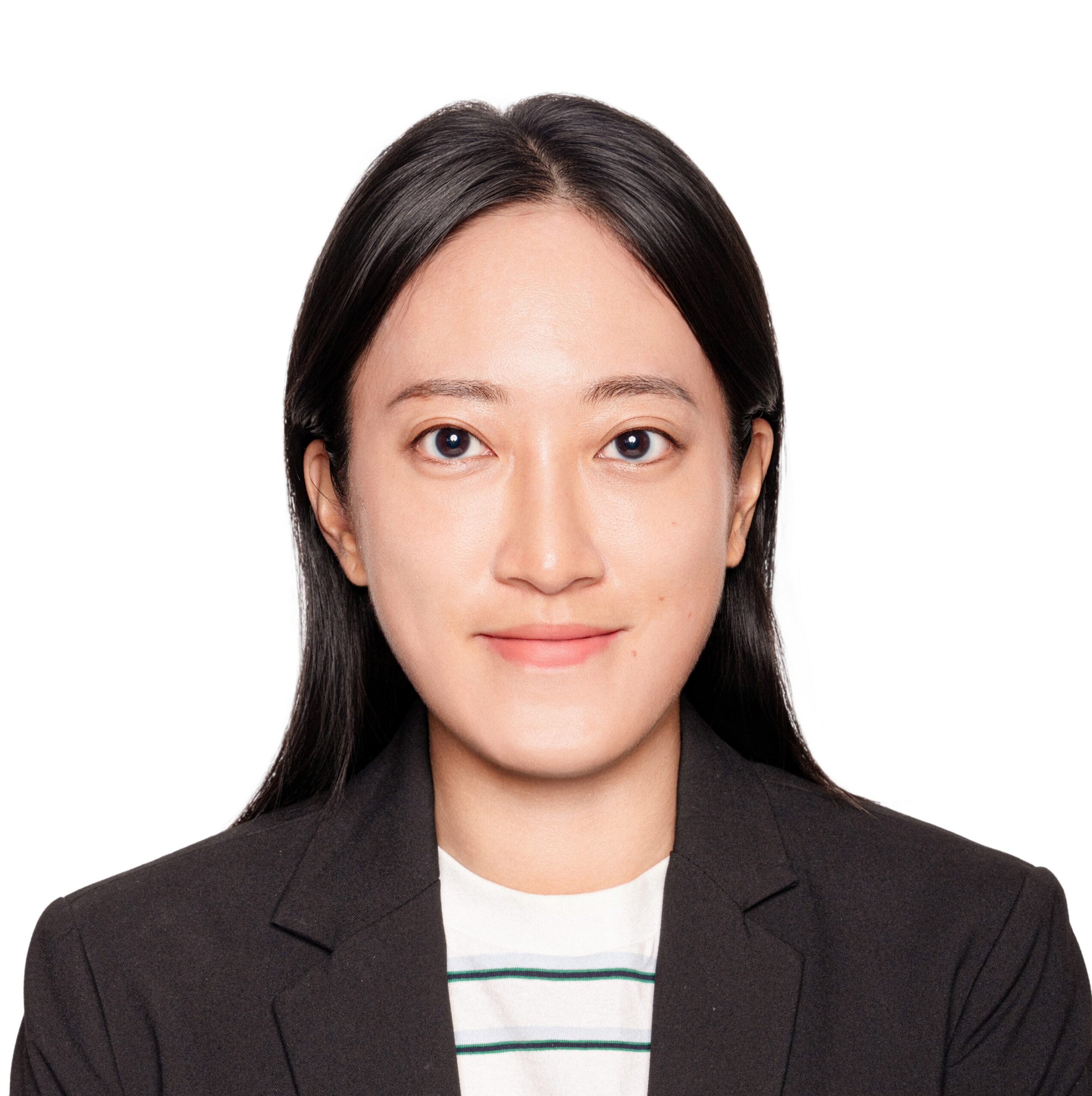 A woman with long dark hair, wearing a black blazer over a white shirt with green stripes, smiles slightly while facing forward against a plain white background.