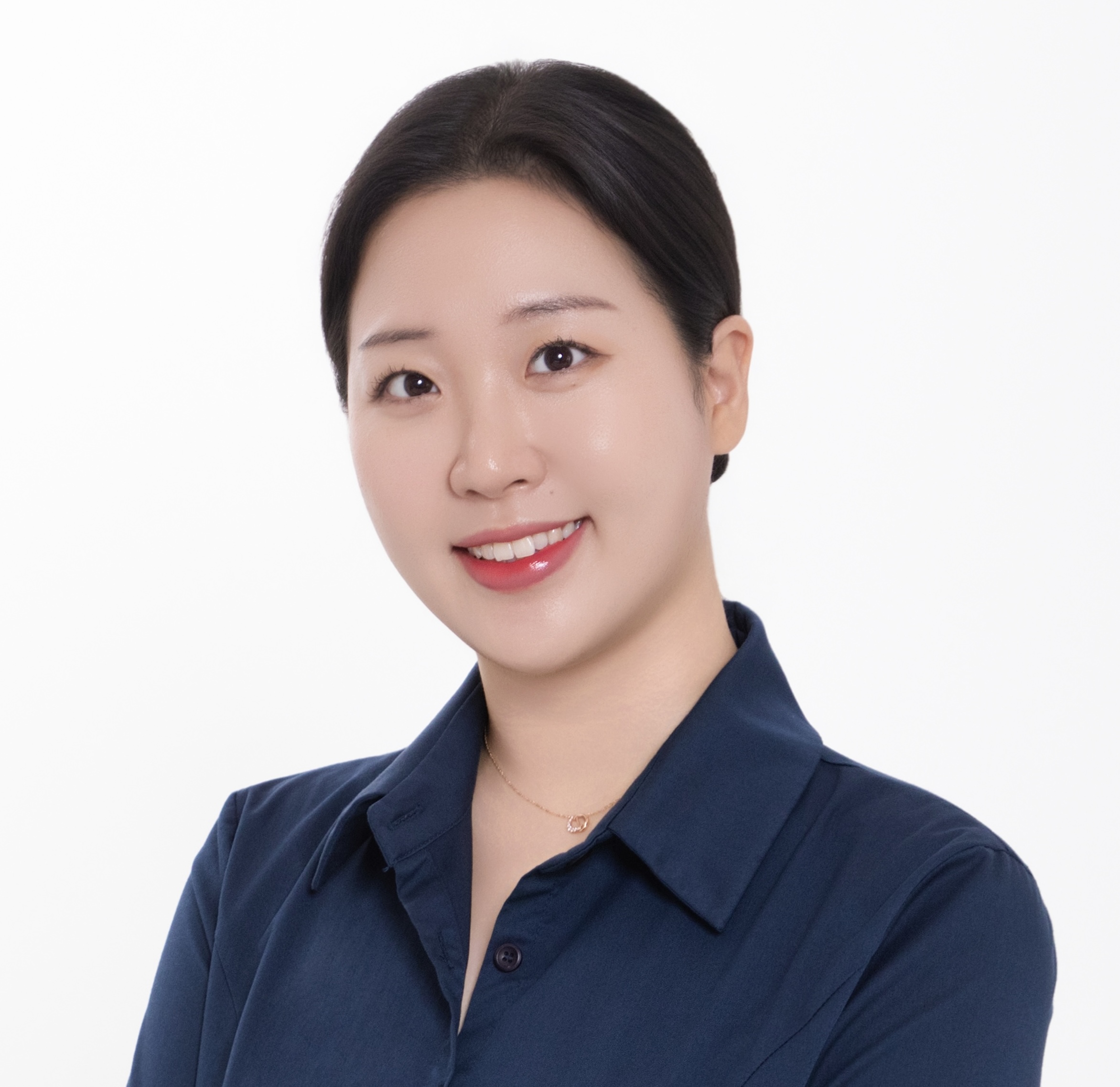 A woman with dark hair pulled back, wearing a navy blue collared shirt, smiles at the camera against a plain white background.